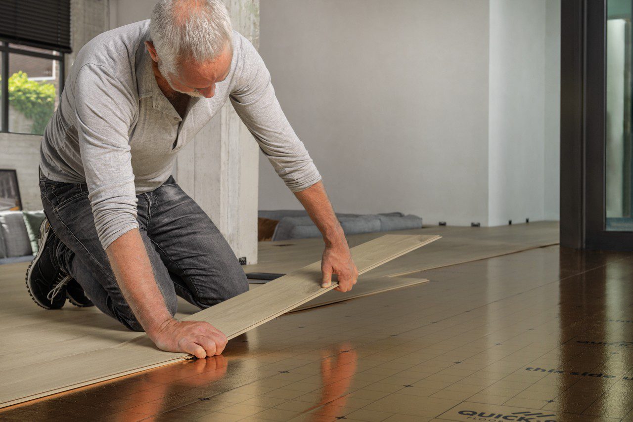 Mies asentaa laminaattilattiaa Pergo Silent Walk alusmateriaalille.