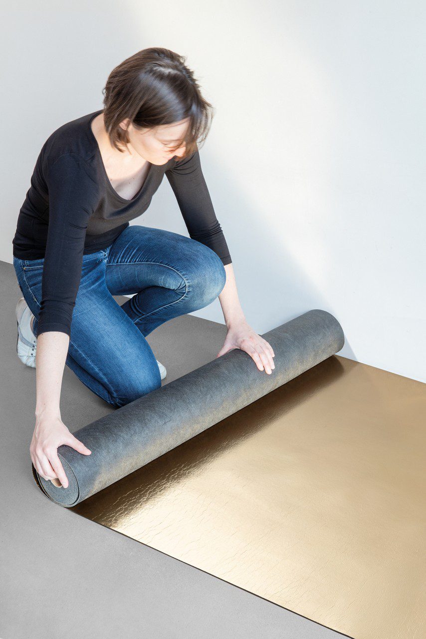 Woman is rolling the Quick-Step SilentWalk parquet and laminate floor underlay roll open on the underfloor