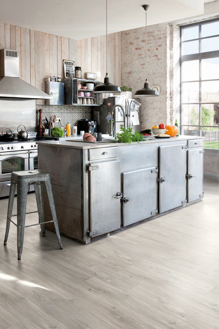 LVT parkett Quick-Step Blos Cayon tamm grey saw cuts paigaldatud köögi põrandale. Metallist köögimööbel ja köögisaar.