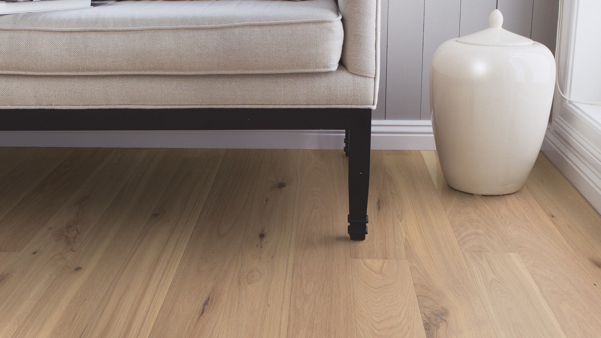 Tammiparketti Bauwerk Boen Casapark tammi 46 Vivo Avorio (138 mm), harjattu ja öljyvahattu, asennettuna käytävän lattialle – lähikuva lattiapinnasta, taustalla näkyy osittain sohva. Vaalea Avorio-sävy ja rustiikkinen sorteerus korostavat tammen eläväistä kuviointia.