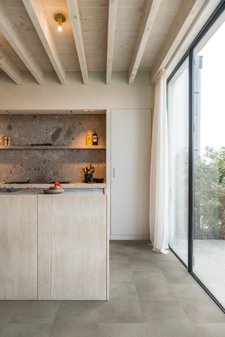 Vinylboden in Steinoptik Quick-Step Oro Concrete Rock, verlegt auf dem Küchenboden – Kücheninsel mit Betonarbeitsplatte und moderne Küchenschränke.