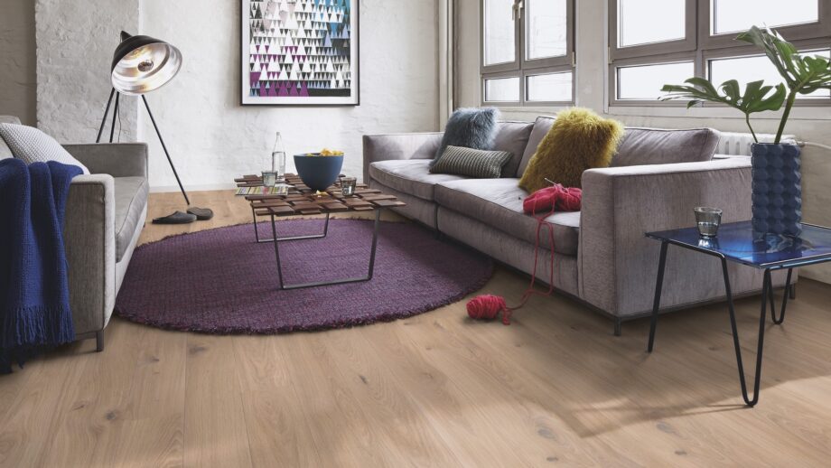 Laudparkett Bauwerk Casapark tamm 46 Crema harjatud ja heleda Bprotect lakiga viimistletud. Parkett on paigaldatud elutoa põrandale. Kaks diivanit ja disainer diivanilaud millel kauss kartulikrõpsudega, veepudel ja veeklaasid.