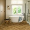 herringbone-laminate-floor-quick-step-impressive-design-cinnamon-oak Herringbone laminate floor Quick-Step Impressive Suunnittelu Cinnamon installed to bathroom floor. White separatly standind bathtub