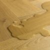 Laminaatparkett kalasaba Quick-Step Impressive Suunnittelu Cumin Oak naturaalne toon ja sorteering. Veelomp laminaadil viitamaks selle veekindlusele.