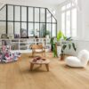 Klick Vinyl Quick Step Bloom Elegant Oak Natural im Wohnzimmer verlegt, Sessel, Tisch, Regal und Topfpflanzen.