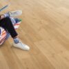Klick Vinylboden Quick Step Bloom Elegant Oak Natural im Wohnzimmer verlegt, ein Mann sitzt in einem Sessel.