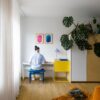 klickvinyl-quick-step-bloom-botanic-smoked-oak Klickvinyl Quick Step Bloom Botanic Smoked Oak im Wohnzimmer verlegt, orangefarbener Liegesessel, ein Mann sitzt auf einem Stuhl und spielt einen Synthesizer.