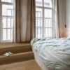 rigid-lvt-flooring-quick-step-bloom-elegant-fumed-oak Rigid LVT flooring Quick-Step Bloom Elegant Fumed Oak installed on a bedroom floor. Big bed, Classical design widows from Ceiling to Floor.