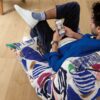 Rigid Vinyl flooring Quick-Step Bloom Elegant Oak Natural installed on ling room floor, man sitting on a chair and looking phone.