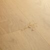 Vinyylilattia Quick Step Bloom Elegant Oak Natural, luonnollinen tammen sävy ja lankkudesign, pinnalla vesipisaroita korostamassa lattian vedenkestävyyttä.
