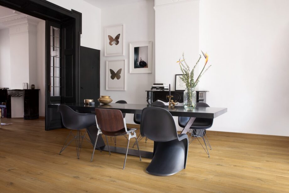 виниловыи-ламинат-quick-step-bloom-cotton-oak-deep-natural Виниловый ламинат Quick Step Bloom Cotton Oak Deep Natural уложен на полу в столовой, современный обеденный стол с каменной столешницей, стулья вокруг стола, на столе цветы.