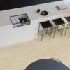 Виниловый ламинат Quick Step Bloom Sea Breeze Oak Beige уложен на полу на кухне, стильный каменный кухонный остров и стулья.
