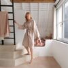 lvt-porand-quick-step-illume-soft-blush LVT põrand Quick-Step Illume Soft blush paigaldatud koridori põrandale. Naine hommikumantlis hoiab kinni redelist.