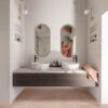 lvt-quick-step-illume-soft-blush LVT Quick-Step Illume Soft blush paigaldatud vannitoa põrandale. Topelt vannitoamööbel valgest marmorist tasapinnaga millel kaks stiilset tasapinnapealset valamut. Seinapeeglist paistab naisterahvas.