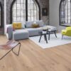 parkett-bauwerk-boen-casapark-eiche-46-gebuerstet-farina-weiss-geoelt Parkett Bauwerk Boen Casapark Eiche 46 Farina, gebürstet und weiß geölt – verlegt auf dem Wohnzimmerboden; graues Sofa, leuchtend grüner Sessel und ein grauer Teppich mit zwei kleinen runden Couchtischen. Rustikale Sortierung mit lebendiger Maserung und Astanteilen.