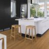 puitparkett-bauwerk-casapark-budget-cut-tamm-35-harjatud-matt-lakk Puitparkett Bauwerk Casapark Budget Cut harjatud matt lakk paigaldatud köögi põrandale. Tume köögimööbel. Valge köögisaar koos puidust toolidega.