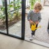 vinyl-flooring-tiles-quick-step-illume-oyster-concrete LVT flooring tiles Quick-Step Illume Oyster concrete with light grey color installed in hallway and kid is coming inside from summer garden.