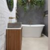 vinylbonden-beton-quick-step-illume-oyster-concrete Vinylboden in Betonoptik Quick-Step Illume Oyster Concrete, verlegt im klassisch eingerichteten Badezimmer – freistehende Badewanne, Badmöbel mit Aufsatzwaschbecken auf Betonplatte sowie Wandarmaturen und Wannenmischer in Bronzeton.